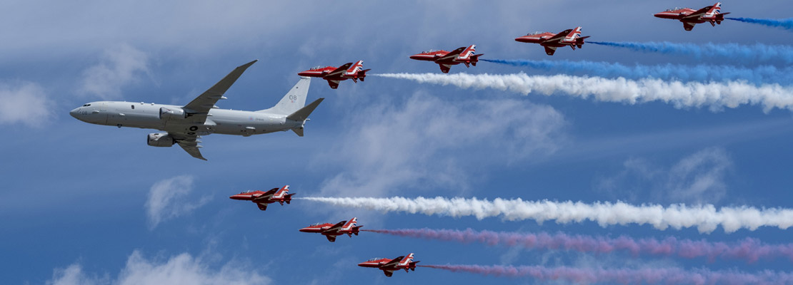 A P-8 inflight with the Red Arrows flying in formation