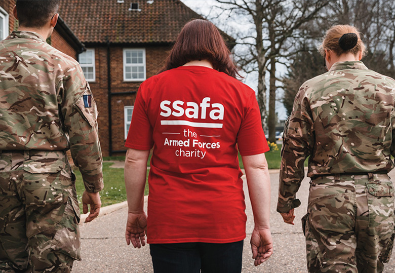 Two military members and a person in a red SSAFA shirt walking together.