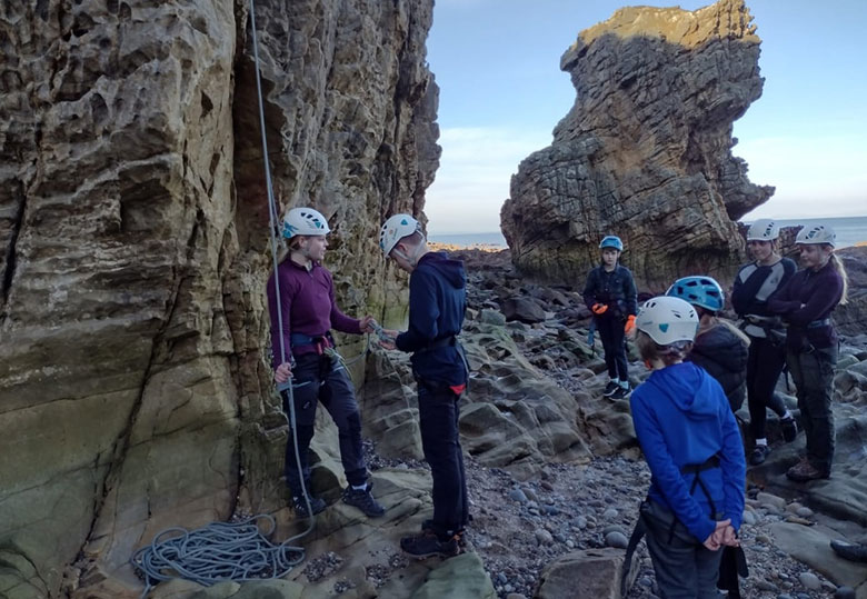 Group of climbers at the foot of a rock, preparing to climb
