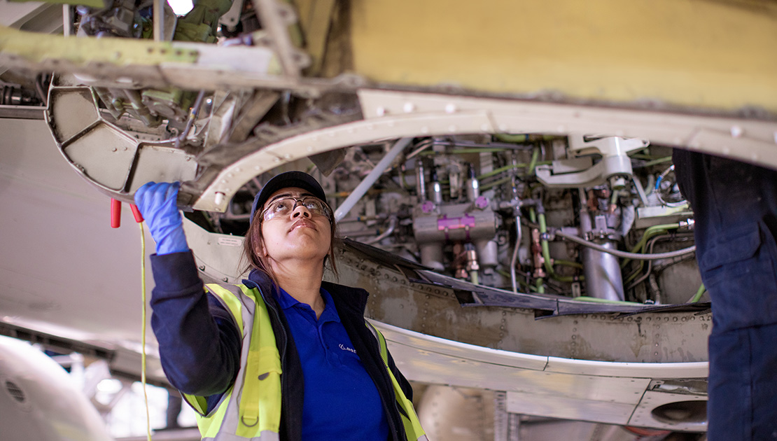 Female Boeing engineer looking at wiring under an aircraft