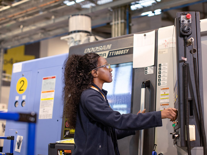 A female factory worker using a machine